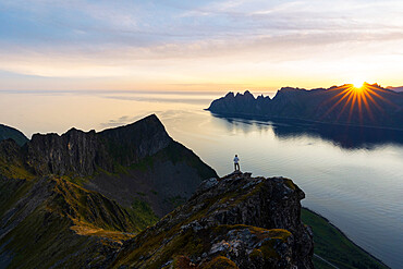 Tourist contemplating the fjord at dawn standing on top of Husfjellet mountain, Senja island, Troms county, Norway, Scandinavia, Europe