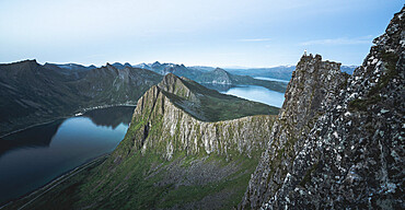 Hiker looking at the fjord at dusk from top of Husfjellet mountain, Senja island, Troms county, Norway, Scandinavia, Europe