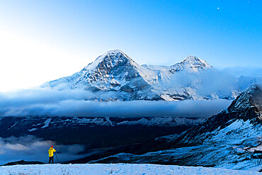 Man with tripod in the snow photographing Eiger and Monch mountain peaks at night, Mannlichen, Bern Canton, Swiss Alps, Switzerland, Europe