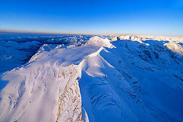 Aerial view of snowy peaks Piz Palu, Piz Zupo and Piz Bernina lit by sunrise, Engadine, Graubunden Canton, Switzerland, Europe