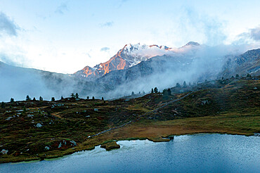 Aerial view of Fletschhorn and Galehorn mountains in fog at dawn from Hopschusee lake, Simplon Pass, Valais canton, Swiss Alps, Switzerland, Europe