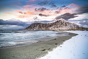 Clouds at sunset over mountain peak covered with snow and icy Skagsanden beach, Flakstad, Lofoten Islands, Norway, Scandinavia, Europe