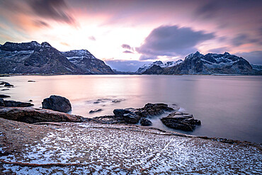 Clouds at dawn over the cold sea and Vareid beach covered with snow, Flakstad, Nordland county, Lofoten Islands, Norway, Scandinavia, Europe