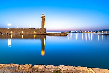 Old lighthouse reflected in the calm sea during the blue hour, Rethymno, Crete island, Greek Islands, Greece, Europe