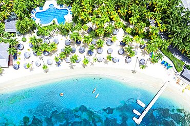 Canoes floating in the tropical lagoon of luxury resort with swimming pool on palm fringed beach, Antigua, Caribbean, West Indies