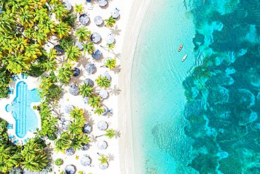 Canoes floating in the crystal sea overlooking a tropical sand beach with swimming pool, Antigua, Caribbean, West Indies