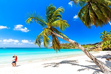 Cheerful little boy with mother walking on idyllic palm fringed beach, Antigua, Leeward Islands, Caribbean, West Indies