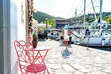 Woman looking at sailboats in the small harbor of the coastal village of Fiskardo, Kefalonia, Ionian Islands, Greek Islands, Greece, Europe