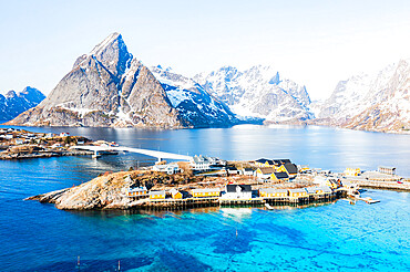 Aerial view of Olstind mountain peak and turquoise sea surrounding Sakrisoy village and Reine Bay, Lofoten Islands, Norway, Scandinavia, Europe