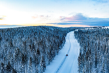 Car traveling into the snowy forest at sunset, aerial view, Gallivare, Norrbotten County, Lapland, Sweden, Scandinavia, Europe