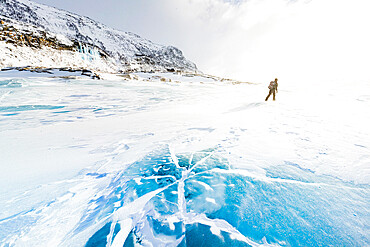 Hiker exploring the snowy landscape walking on icy lake in winter, Stora Sjofallet, Norrbotten County, Lapland, Sweden, Scandinavia, Europe