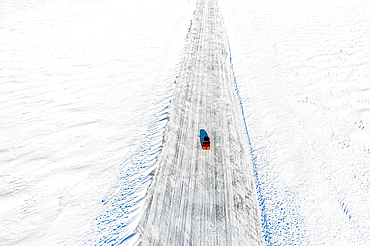 Cold winter sun over an isolated car traveling on ice road on frozen sea, aerial view, Lulea, Norrbotten County, Lapland, Sweden, Scandinavia, Europe