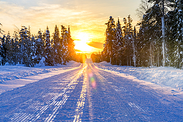 Sunset over an empty snowy road, Lapland, Finland, Europe