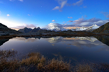 Snowy peak of Monte Disgrazia reflected in water at night, Alpe Fora, Valmalenco, Valtellina, Sondrio province, Lombardy, Italy, Europe