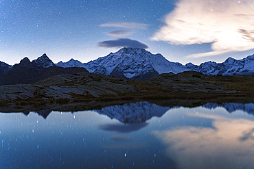 Starry sky over the snowy Monte Disgrazia reflected in water, Alpe Fora, Valmalenco, Valtellina, Sondrio province, Lombardy, Italy, Europe