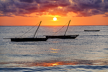 Cloudy sky at sunrise over silhouettes of boats moored in the sea, Jambiani, Zanzibar, Tanzania, East Africa, Africa