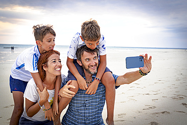 Happy family with two boys snapping a selfie with smartphone on a beach, Zanzibar, Tanzania, East Africa, Africa