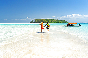 Man and woman in love holding hands walking on empty sandy shore surrounded by the Indian Ocean, Zanzibar, Tanzania, East Africa, Africa