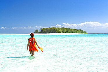 Woman admiring an exotic island standing in the crystal blue sea, Zanzibar, Tanzania, East Africa, Africa