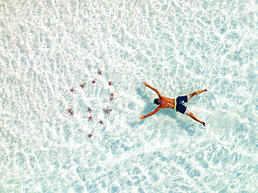 Aerial view of tourist admiring the colorful starfish snorkeling in the turquoise lagoon, Zanzibar, Tanzania, East Africa, Africa