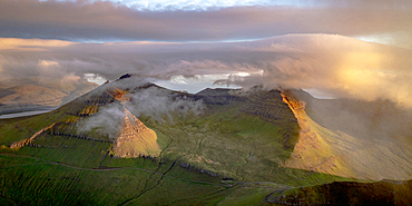 Foggy sunrise over Slaettaratindur peak, highest mountain of Faroe Islands, aerial view, Eysturoy Island, Denmark, Europe