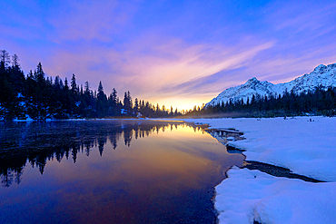 Multicolored sky at dawn reflected in the pristine water of lake Entova, Valmalenco, Valtellina, Lombardy, Italy, Europe