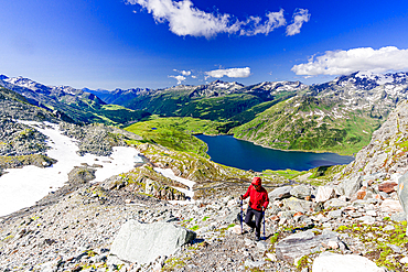 Hiker walking on mountain ridge above the blue lake Montespluga, Madesimo, Valle Spluga, Valtellina, Lombardy, Italy, Europe