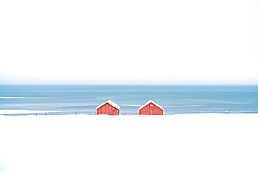 Red cabins in the snow overlooking the frozen sea, Troms county, Norway, Scandinavia, Europe