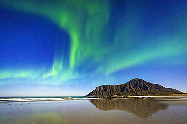 Aurora Borealis (Northern Lights) over mountains reflected on Skagsanden beach washed by waves, Ramberg, Lofoten Islands, Nordland, Norway, Scandinavia, Europe