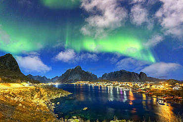 Illuminated harbor of Reine under the bright green lights of the Aurora Borealis (Northern Lights), Lofoten Islands, Nordland, Norway, Scandinavia, Europe