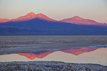 The profiles of two volcanos of the Cordillera de la Sal reflecting in a pool in the Desert of Atacama, Chile, South America