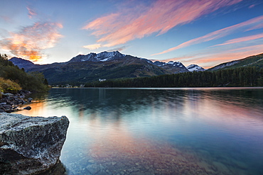 Pink sky at dawn illuminates the peaks reflected in Lake Sils, Engadine, Canton of Graubunden, Switzerland, Europe