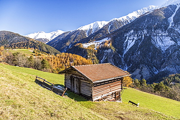 Wooden cabin surrounded by colorful woods and snowy peaks, Schmitten, Albula District, Canton of Graubunden, Switzerland, Europe