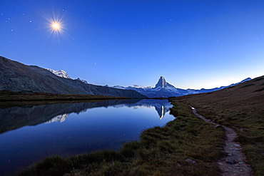 Full moon and Matterhorn illuminated for the 150th anniversary of the first ascent, reflected in Lake Stellisee, Zermatt, Canton of Valais, Swiss Alps, Switzerland, Europe