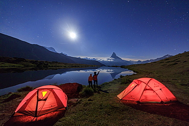 Hikers admire Matterhorn reflected in Lake Stellisee on a starry night of full moon, Zermatt, Canton of Valais, Swiss Alps, Switzerland, Europe