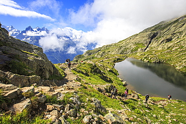 Low clouds and mist around Grandes Jorasses and Mont Blanc while hikers proceed on Lac De Cheserys, Haute Savoie, French Alps, France, Europe