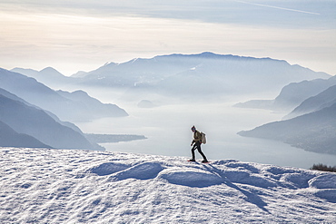 Winter view of Lake Como while a hiker proceeds with snowshoes, Vercana mountains, High Lario, Lombardy, Italy, Europe