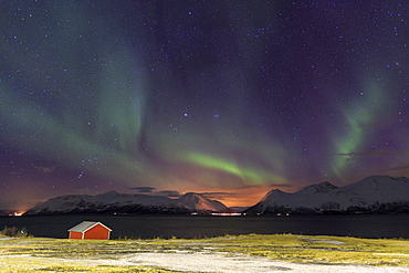 Northern Lights illuminates the wooden cabin at Svensby, Lyngen Alps, Troms, Lapland, Norway, Scandinavia, Europe