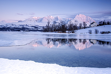 Snowy peaks are reflected in the frozen Lake Jaegervatnet at sunset, Stortind, Lyngen Alps, Tromso? Lapland, Norway, Scandinavia, Europe