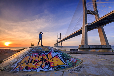 A tourist admires the majestic Vasco da Gama Bridge over the River Tagus, Parque das Nacoes, Lisbon, Portugal, Europe