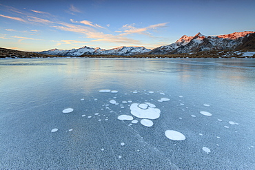 Ice bubbles on the frozen surface of Andossi Lake at sunrise, Spluga Valley, Valtellina, Lombardy, Italy, Europe