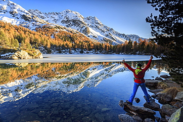 Hiker rejoices in the colourful autumnal landscape around Saoseo Lake, Poschiavo Valley, Canton of Graubuenden, Switzerland, Europe