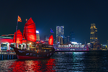 Traditional sailing boat with red sails at night, with high rise buildings behind in Central Hongkong, China, Asia