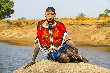 Mundari woman in a traditional dress with face covered in ash posing on a rock, Mundari tribe, South Sudan, Africa