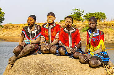 Mundari women in traditional dresses, with facial scarring and ash on faces, posing on a rock, Mundari tribe, South Sudan, Africa