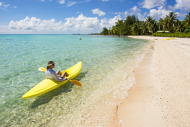 Woman kayaking in the turquoise waters of Tikehau, Tuamotus, French Polynesia, Pacific