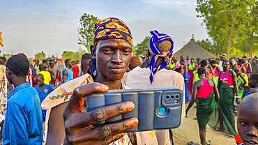 Man with cellphone taking a photo at a traditional Dinka wedding, Bor, central region, South Sudan, Africa