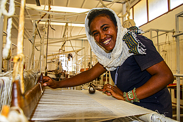 Friendly woman working on a hand weaving loom on a social project in the highlands of Eritrea, Africa