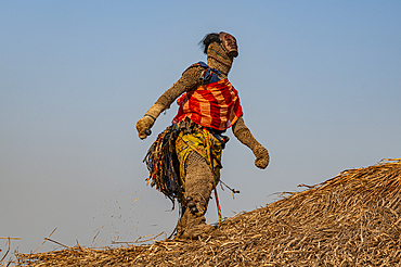 Traditional masked man dancing on a roof of a hut, Tshikapa, Kasai, Democratic Republic of Congo, Africa