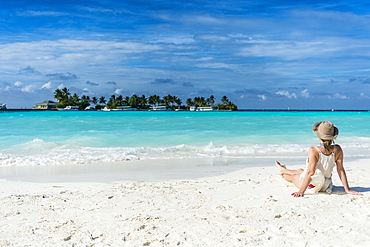 Woman sitting on a white sand beach enjoying the turquoise water, Sun Island Resort, Nalaguraidhoo island, Ari atoll, Maldives, Indian Ocean, Asia